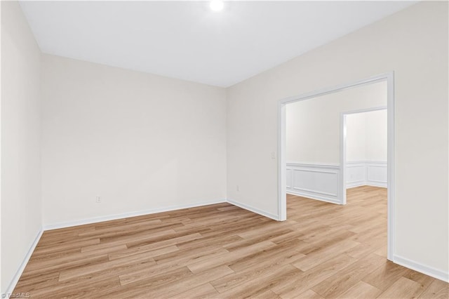 spare room with a decorative wall, light wood-style floors, and baseboards