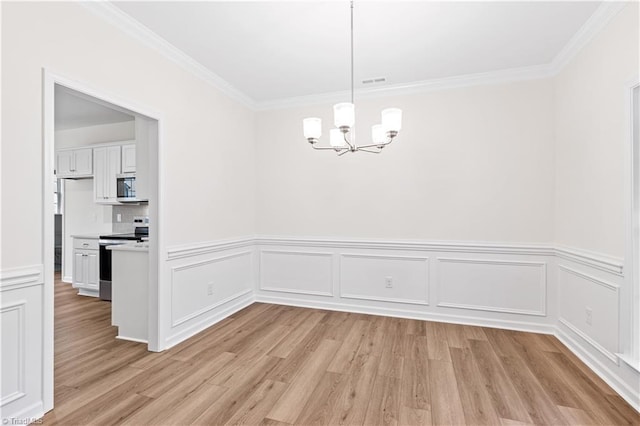 unfurnished dining area with a chandelier, crown molding, and light wood-type flooring