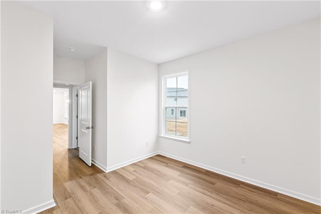 empty room featuring baseboards and light wood finished floors