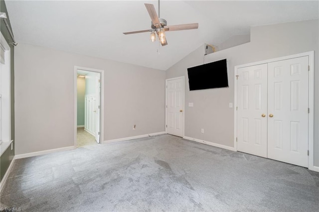 unfurnished bedroom featuring ensuite bath, ceiling fan, carpet floors, vaulted ceiling, and a closet