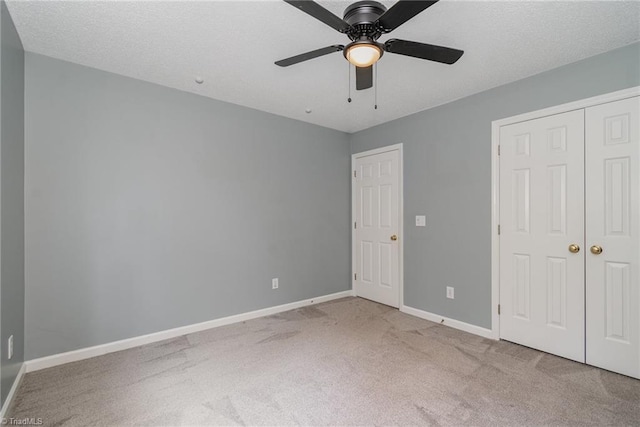 unfurnished bedroom featuring light carpet, a textured ceiling, ceiling fan, and a closet