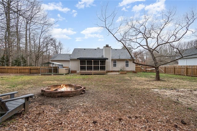 back of property with a sunroom and an outdoor fire pit