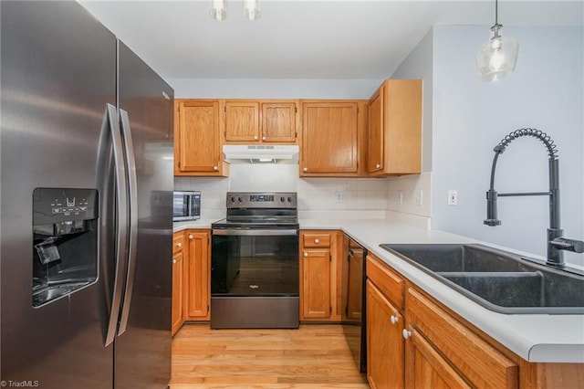 kitchen featuring sink, hanging light fixtures, stainless steel appliances, light hardwood / wood-style floors, and decorative backsplash