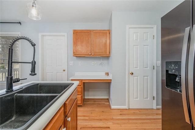 kitchen with sink, decorative light fixtures, stainless steel fridge, and light hardwood / wood-style floors