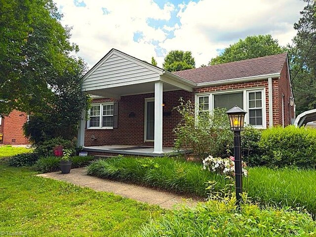 211 Hermitage Rd, Greensboro, NC 27403 - view of front of house featuring brick siding, covered porch, and a front yard