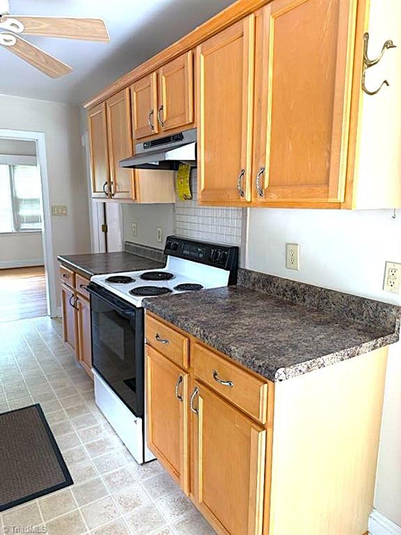 211 Hermitage Rd, Greensboro, NC 27403 - kitchen featuring range with electric cooktop, under cabinet range hood, a ceiling fan, tasteful backsplash, and brown cabinetry