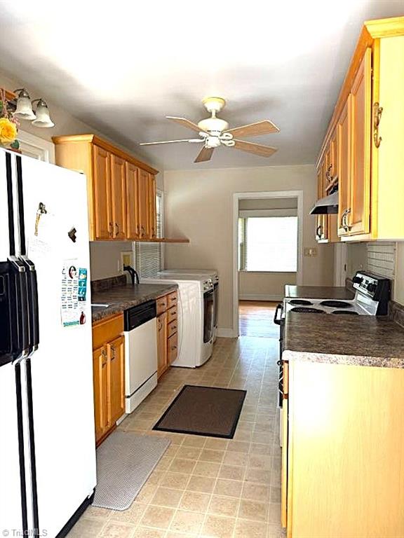 211 Hermitage Rd, Greensboro, NC 27403 - kitchen with white appliances, washer / dryer, under cabinet range hood, ceiling fan, and dark countertops
