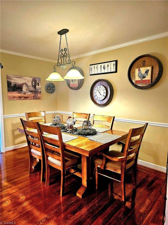 dining space featuring baseboards, wood finished floors, and crown molding