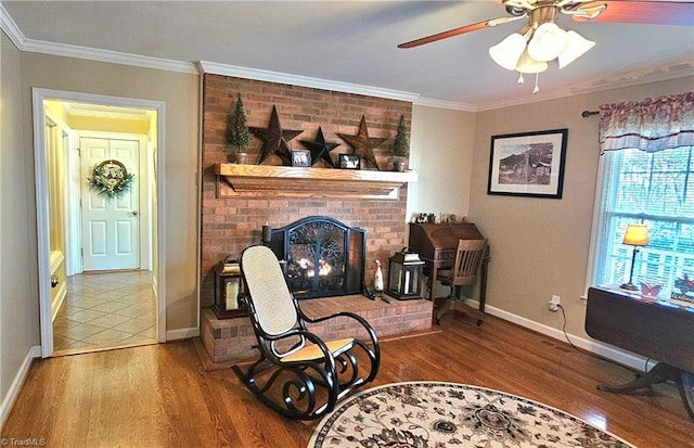 living area with a brick fireplace, crown molding, baseboards, and wood finished floors