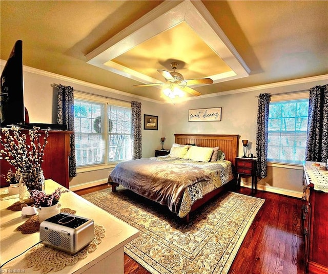 bedroom with baseboards, a tray ceiling, dark wood-style flooring, and crown molding