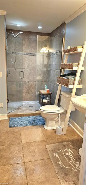 full bath featuring toilet, a shower stall, baseboards, and crown molding