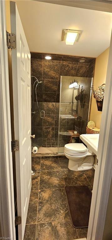 full bath featuring toilet, a stall shower, stone tile floors, and visible vents