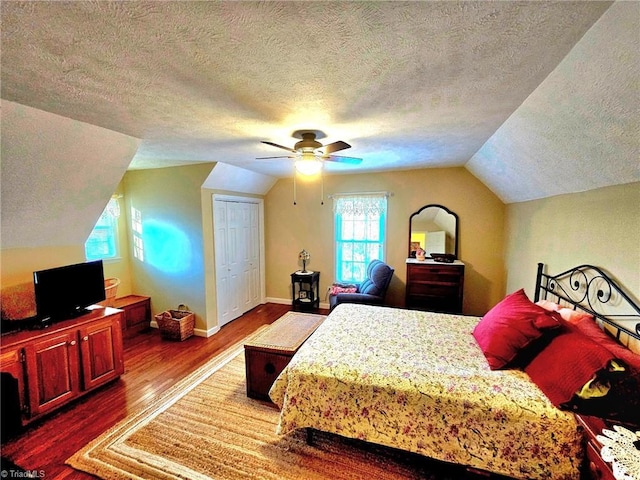 bedroom featuring dark wood-style flooring, vaulted ceiling, a textured ceiling, ceiling fan, and baseboards