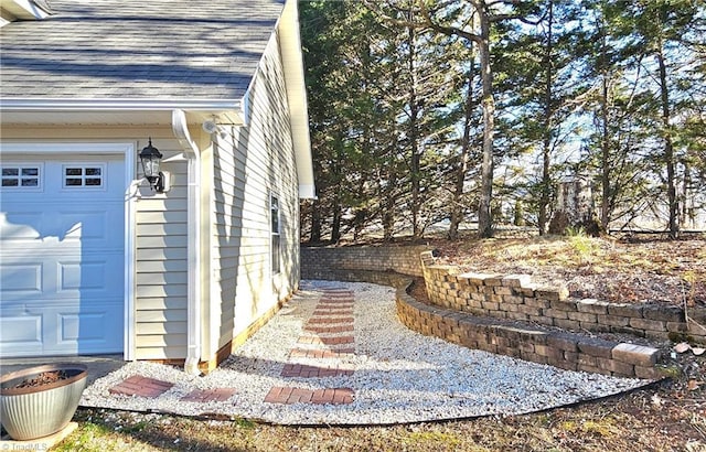 view of home's exterior with a garage and roof with shingles