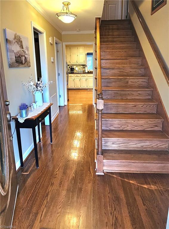 interior space featuring baseboards, ornamental molding, and wood finished floors