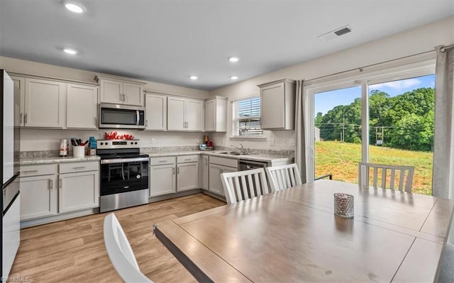 kitchen with stainless steel appliances, light wood-type flooring, light countertops, recessed lighting, and a sink