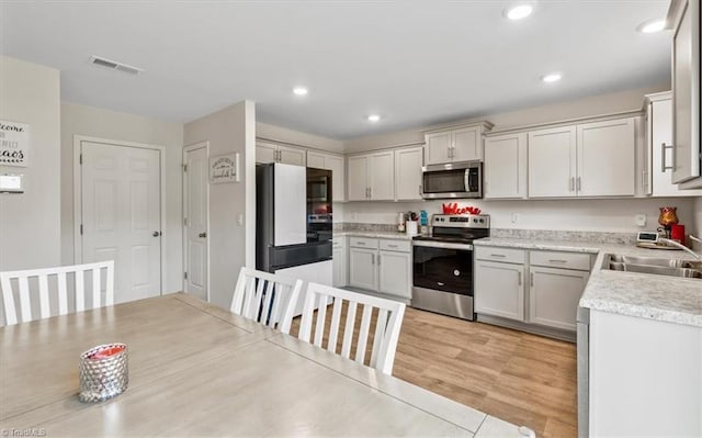 kitchen featuring appliances with stainless steel finishes, a sink, light countertops, and recessed lighting