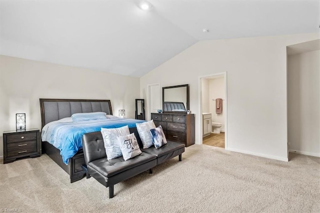 bedroom with light colored carpet, lofted ceiling, baseboards, and ensuite bath