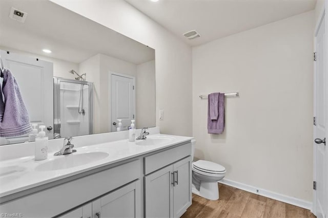 full bathroom with a stall shower, wood finished floors, double vanity, baseboards, and toilet