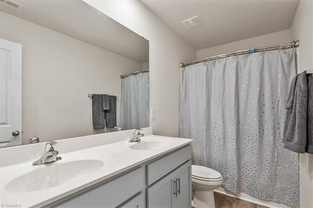 bathroom featuring toilet, double vanity, and curtained shower