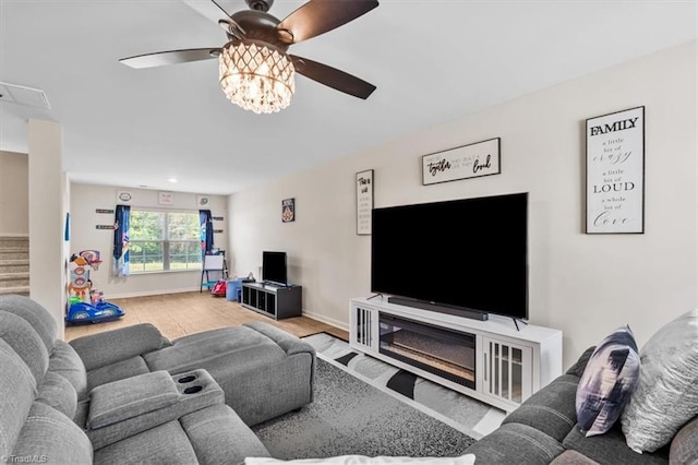 living room featuring wood finished floors, a ceiling fan, and stairway