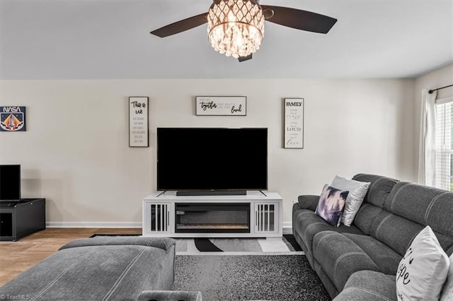 living area featuring a ceiling fan, baseboards, and wood finished floors