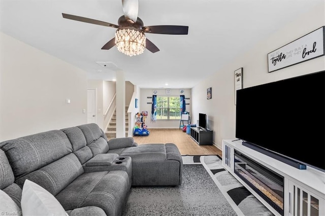 living area with stairs, wood finished floors, and a ceiling fan