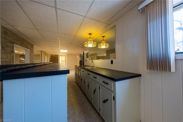 kitchen featuring white cabinets, hanging light fixtures, carpet, and sink