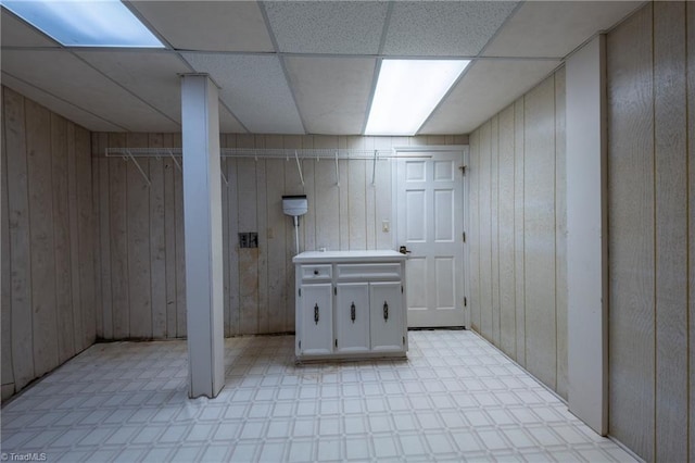 basement with a paneled ceiling and wooden walls