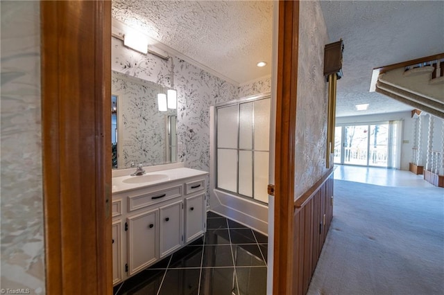 bathroom featuring a textured ceiling, enclosed tub / shower combo, tile patterned floors, and vanity