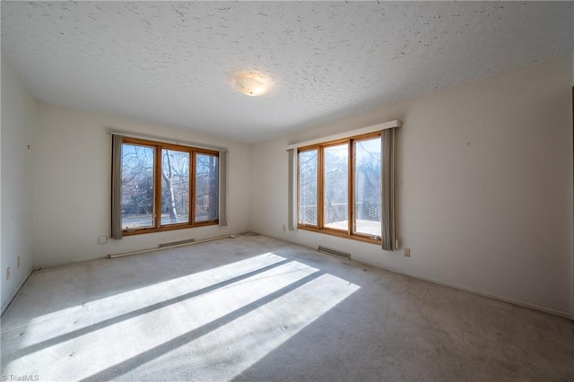 empty room with a textured ceiling and light colored carpet