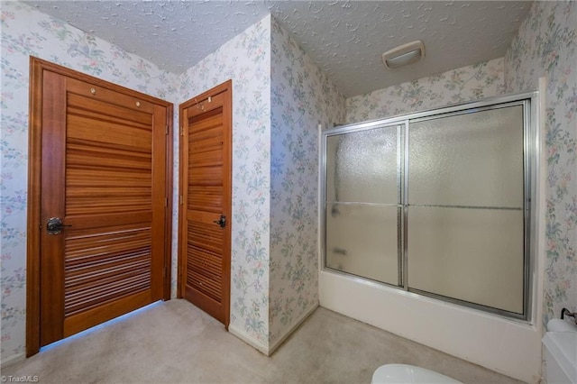 bathroom featuring combined bath / shower with glass door and a textured ceiling