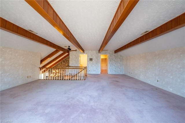 interior space featuring a textured ceiling, ceiling fan, vaulted ceiling with beams, and carpet floors