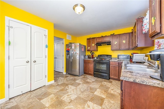 kitchen featuring a sink, baseboards, stone finish floor, under cabinet range hood, and appliances with stainless steel finishes