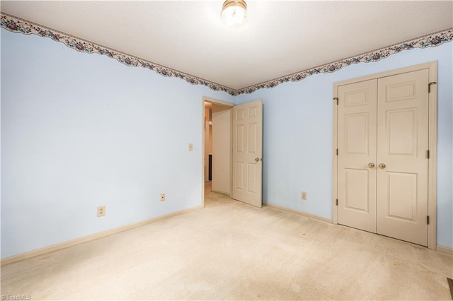 unfurnished bedroom featuring light colored carpet and a closet