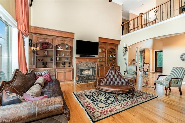 living room with a high ceiling, a premium fireplace, and light wood-style flooring