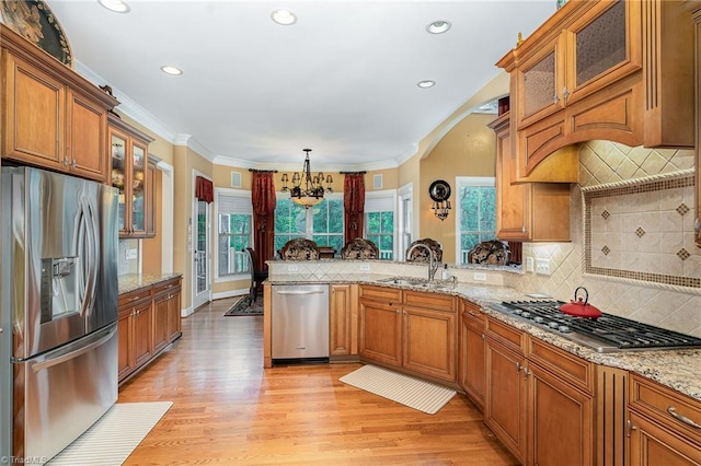 kitchen featuring appliances with stainless steel finishes, a sink, brown cabinets, backsplash, and recessed lighting