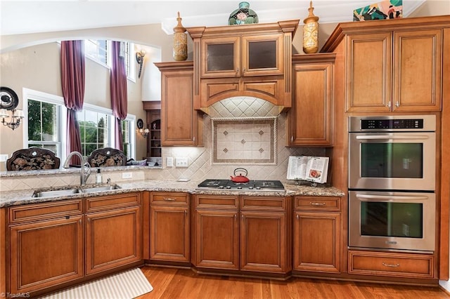 kitchen featuring stainless steel appliances, a sink, and light stone countertops