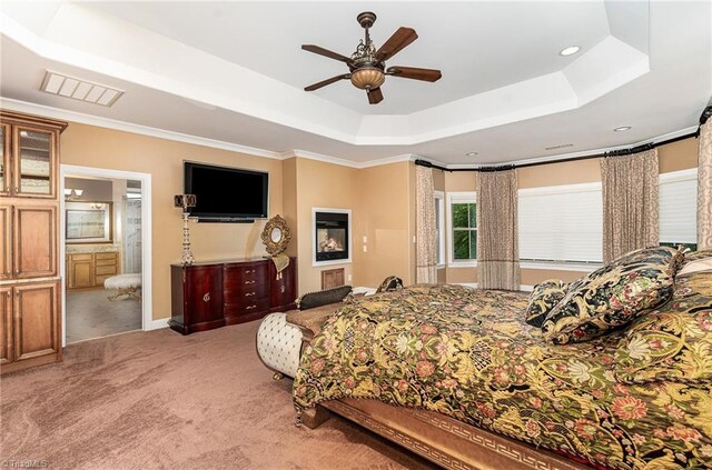 carpeted bedroom featuring a tray ceiling, ceiling fan, and ensuite bathroom