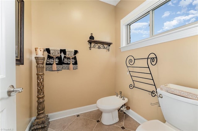 bathroom featuring toilet, tile patterned flooring, a bidet, and baseboards