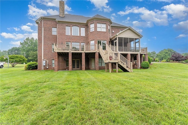 back of property featuring a sunroom, a chimney, stairway, and a yard