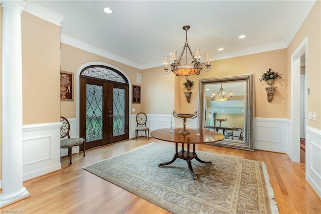 entryway with a chandelier, wainscoting, ornate columns, french doors, and crown molding
