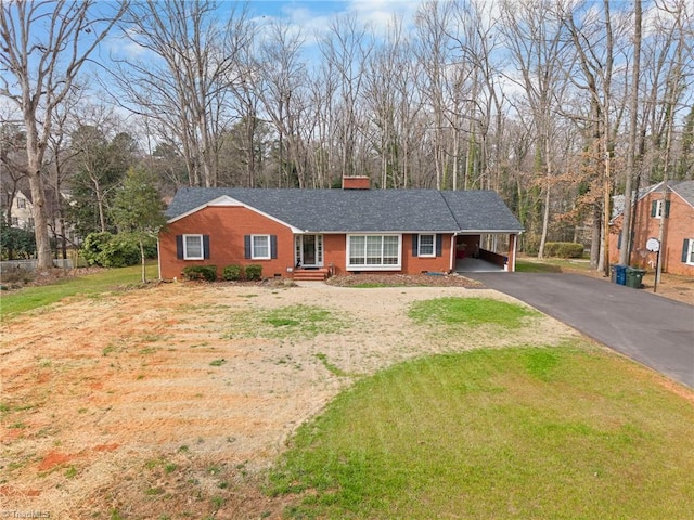 ranch-style home with driveway, roof with shingles, a front yard, a carport, and brick siding