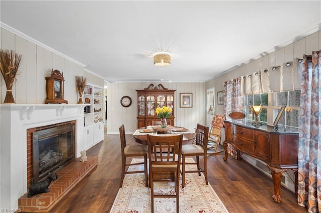 dining area featuring crown molding, a healthy amount of sunlight, a fireplace, and wood finished floors