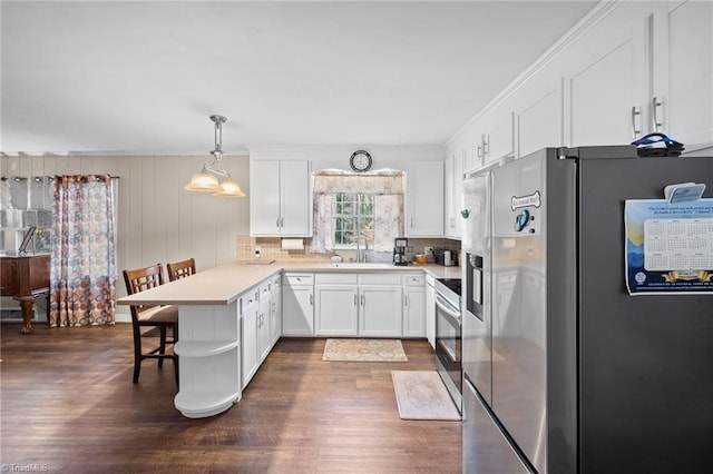 kitchen with light countertops, appliances with stainless steel finishes, dark wood-type flooring, white cabinetry, and a peninsula