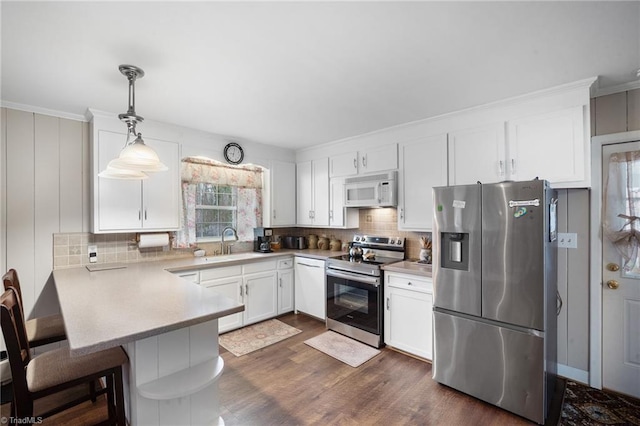 kitchen with appliances with stainless steel finishes, backsplash, white cabinets, and a peninsula