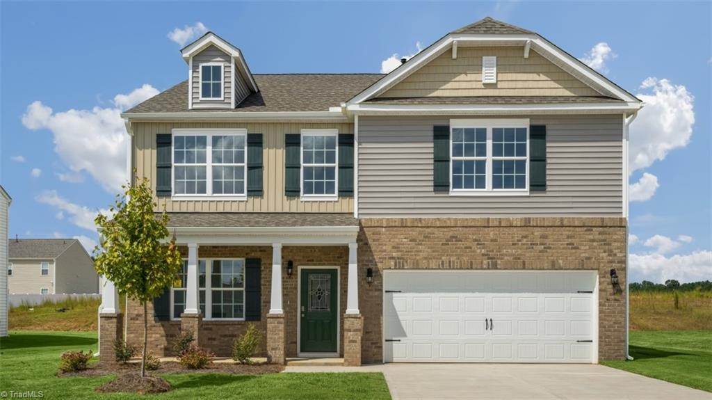 craftsman-style house with a garage, a front lawn, brick siding, and driveway