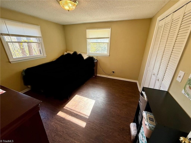 bedroom with a textured ceiling, dark wood-type flooring, and a closet