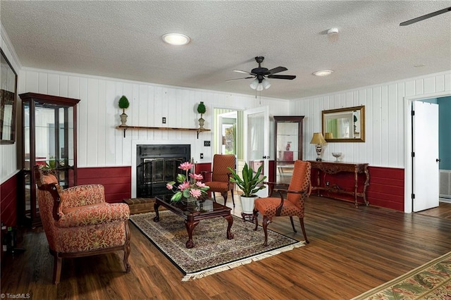 living room featuring a fireplace, dark hardwood / wood-style flooring, a textured ceiling, and ceiling fan