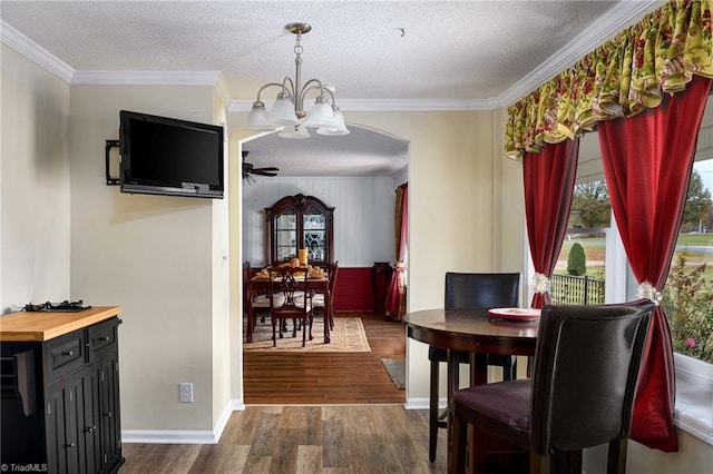 dining area with ceiling fan with notable chandelier, a textured ceiling, dark hardwood / wood-style flooring, and ornamental molding